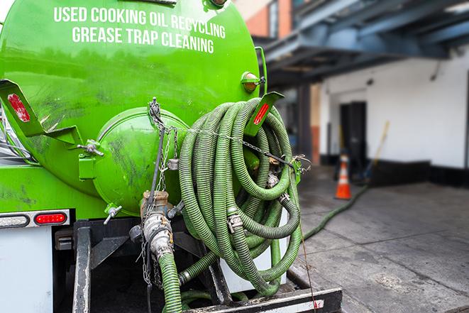 worker pumping grease trap at commercial kitchen in Corning OH