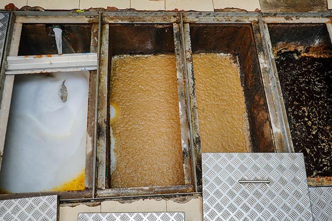 a messy grease trap being emptied and cleaned